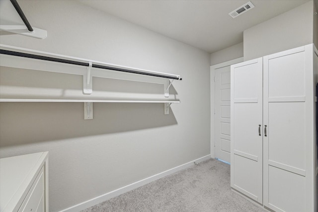 walk in closet featuring light colored carpet