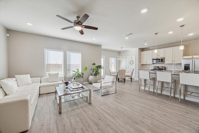 living room featuring ceiling fan, sink, light hardwood / wood-style flooring, and a textured ceiling