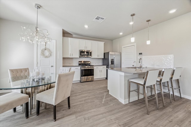 kitchen with sink, decorative light fixtures, white cabinets, and appliances with stainless steel finishes