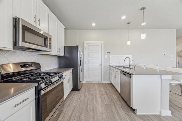 kitchen featuring a breakfast bar, sink, white cabinetry, pendant lighting, and stainless steel appliances