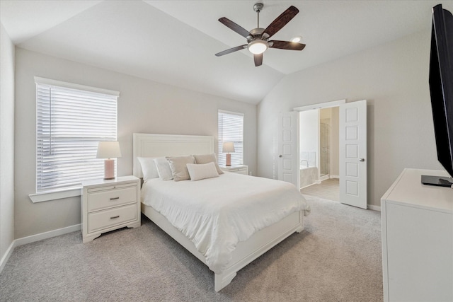 bedroom featuring ceiling fan, ensuite bathroom, vaulted ceiling, and light carpet