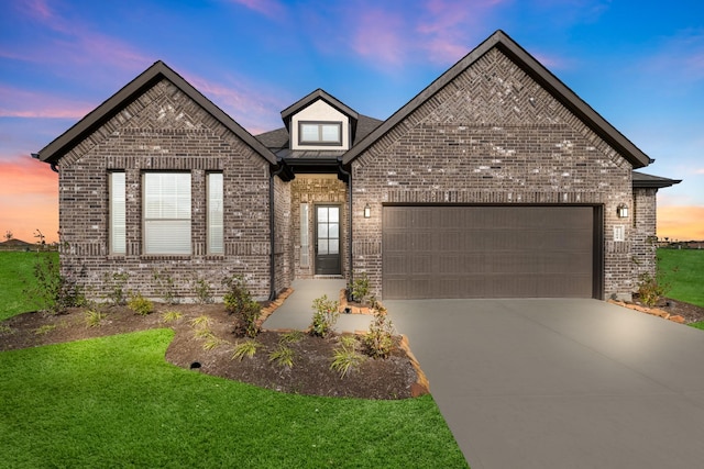 french country inspired facade featuring a yard, brick siding, driveway, and an attached garage