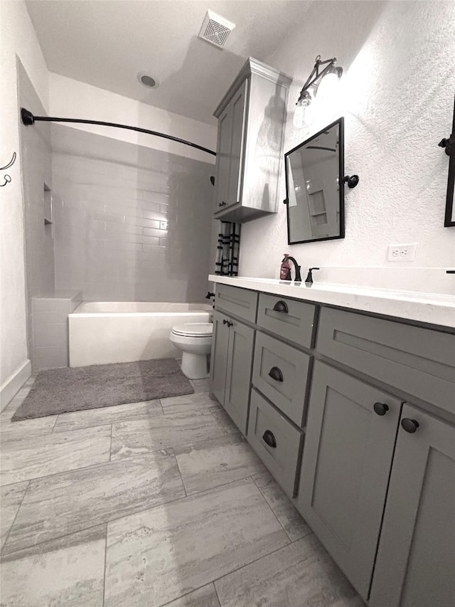 full bathroom featuring tiled shower / bath, vanity, and toilet