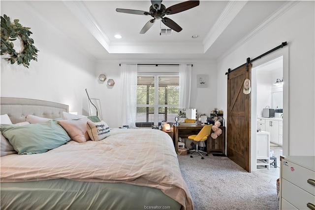 carpeted bedroom featuring a tray ceiling, ornamental molding, a barn door, and ensuite bathroom