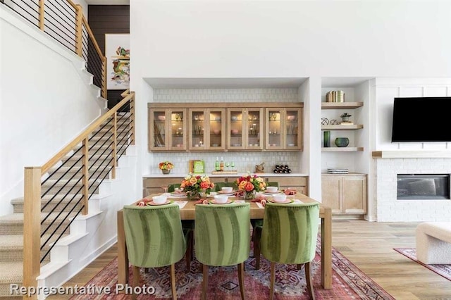 dining space featuring a brick fireplace and light hardwood / wood-style flooring