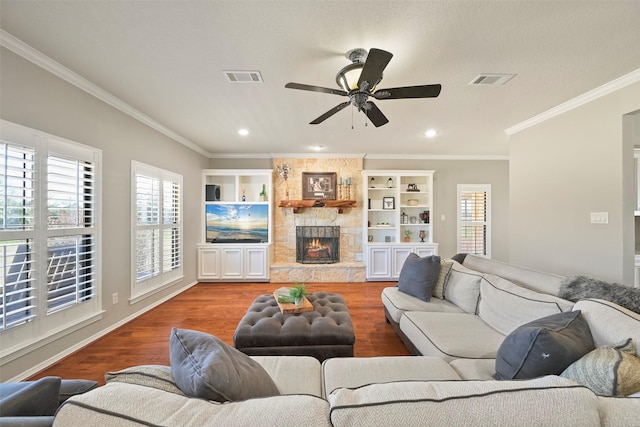 living room featuring ornamental molding, a stone fireplace, hardwood / wood-style floors, and ceiling fan