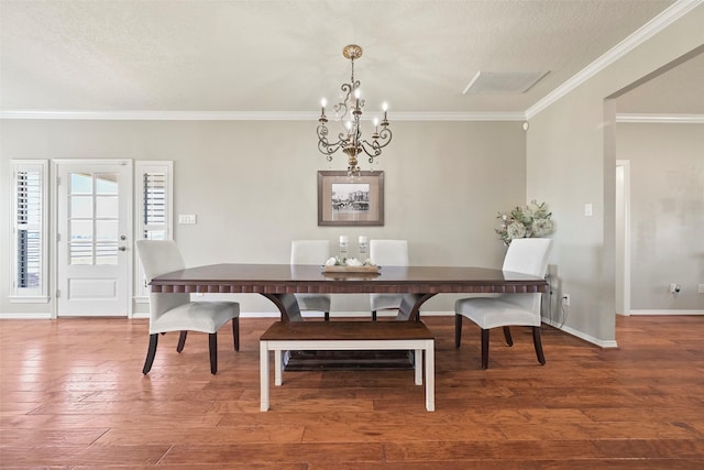 dining area with hardwood / wood-style flooring, ornamental molding, a textured ceiling, and a chandelier