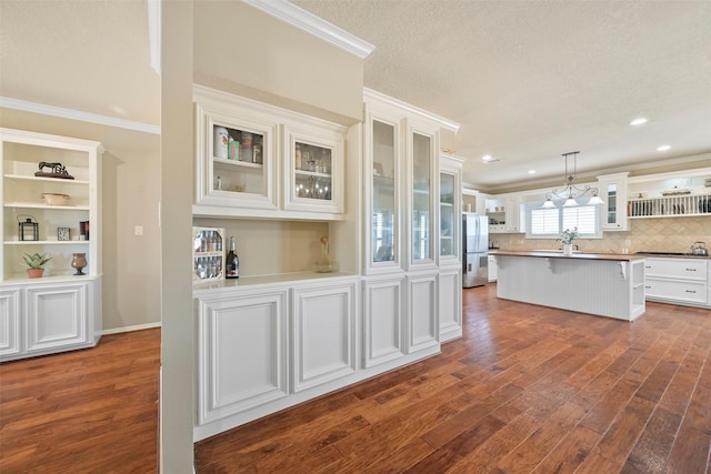 kitchen with white cabinetry, decorative light fixtures, a kitchen breakfast bar, and dark hardwood / wood-style floors