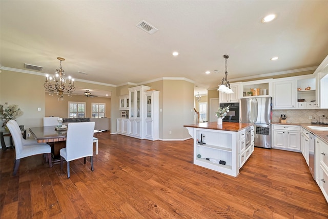 kitchen with white cabinetry, hanging light fixtures, stainless steel appliances, tasteful backsplash, and wood counters