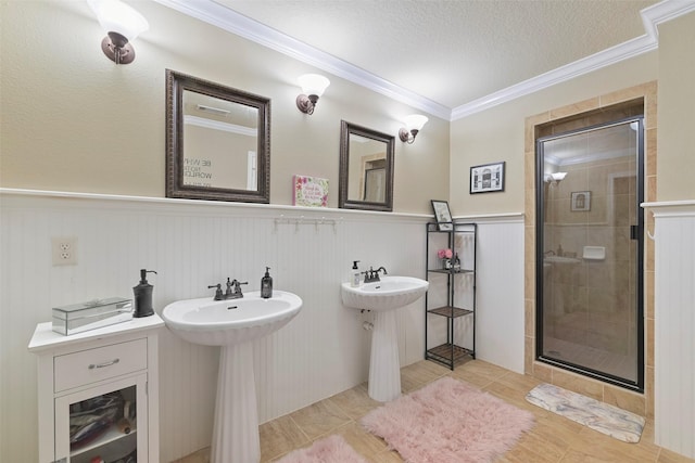 bathroom with an enclosed shower, crown molding, a textured ceiling, and dual sinks