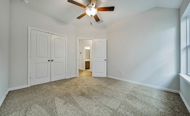 unfurnished bedroom featuring ceiling fan, carpet flooring, vaulted ceiling, and a closet