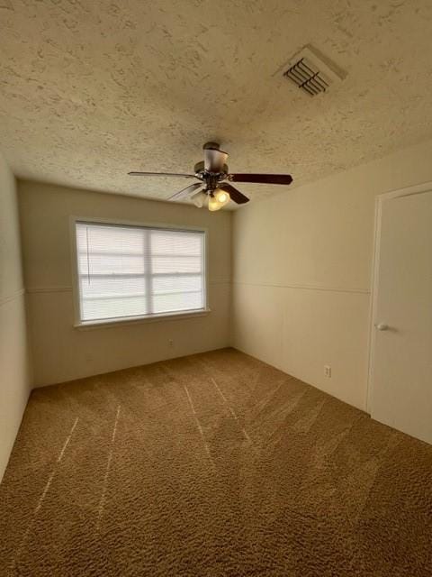 carpeted spare room featuring ceiling fan and a textured ceiling