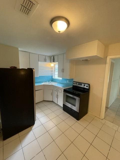 kitchen with white cabinetry, fridge, stainless steel electric range oven, and light tile patterned floors