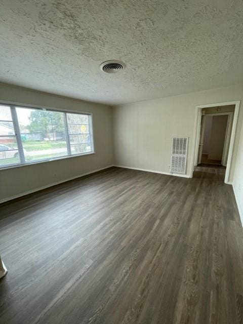 empty room featuring dark wood-type flooring and a textured ceiling