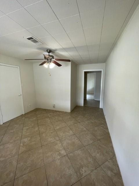 spare room with tile patterned floors, a drop ceiling, and ceiling fan