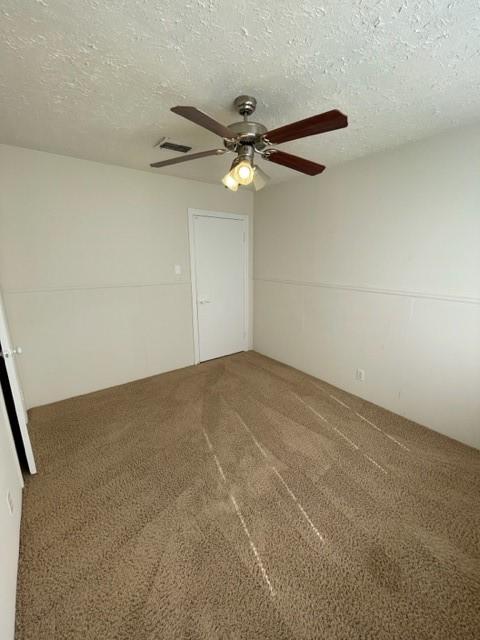 empty room with ceiling fan, a textured ceiling, and carpet flooring