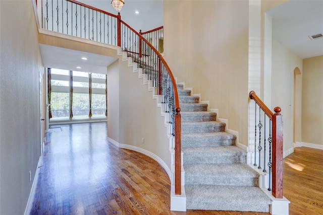 stairway featuring hardwood / wood-style flooring and a high ceiling