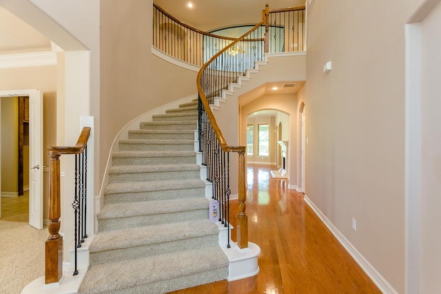 stairway with a towering ceiling and wood-type flooring