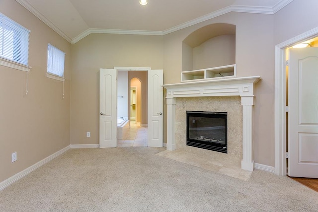 unfurnished living room with light carpet, crown molding, a high end fireplace, and vaulted ceiling