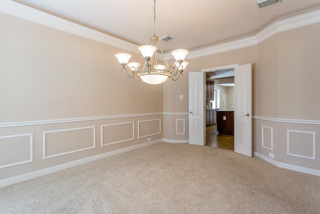 spare room featuring ornamental molding, carpet flooring, and a chandelier