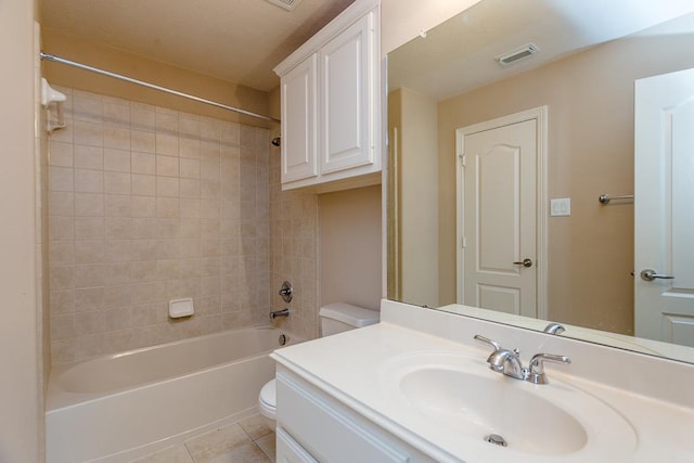 full bathroom featuring tiled shower / bath, vanity, toilet, and tile patterned flooring