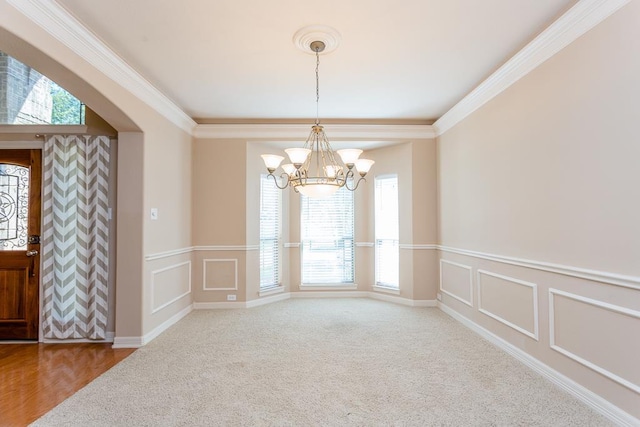 carpeted spare room featuring ornamental molding and a chandelier