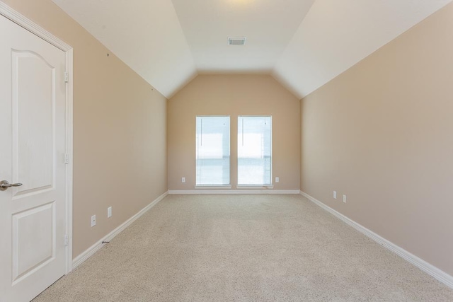 additional living space featuring vaulted ceiling and light colored carpet