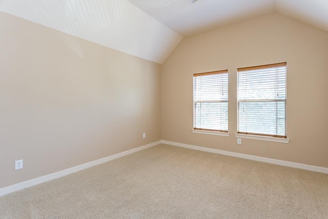 carpeted empty room featuring lofted ceiling