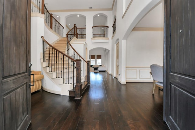 entryway with a towering ceiling, ornamental molding, and dark hardwood / wood-style floors