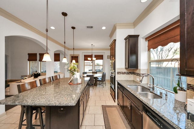 kitchen with pendant lighting, sink, a breakfast bar, backsplash, and a kitchen island