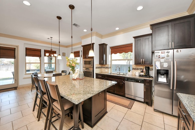 kitchen featuring sink, a kitchen bar, hanging light fixtures, a center island, and stainless steel appliances