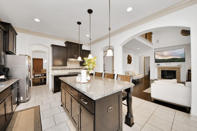 kitchen with tasteful backsplash, decorative light fixtures, dark brown cabinets, a kitchen breakfast bar, and a kitchen island