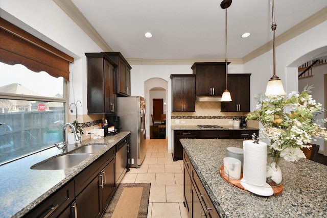 kitchen featuring dark brown cabinetry, sink, hanging light fixtures, appliances with stainless steel finishes, and light stone countertops