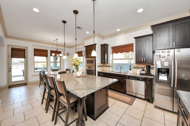 kitchen featuring stainless steel appliances, a kitchen island, hanging light fixtures, and light stone counters