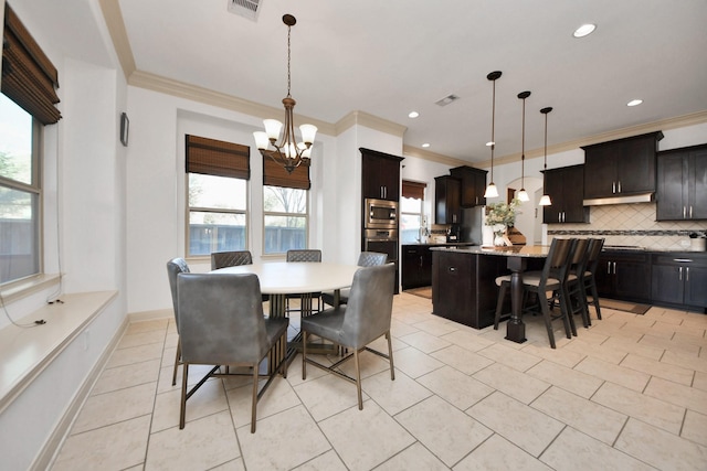 tiled dining space featuring ornamental molding, plenty of natural light, and a chandelier