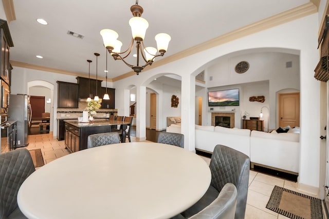 dining area with crown molding, light tile patterned floors, and a chandelier