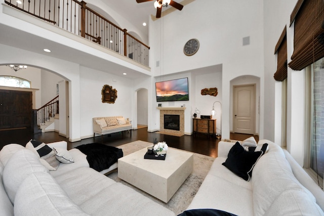 living room featuring hardwood / wood-style flooring, ceiling fan with notable chandelier, and a towering ceiling