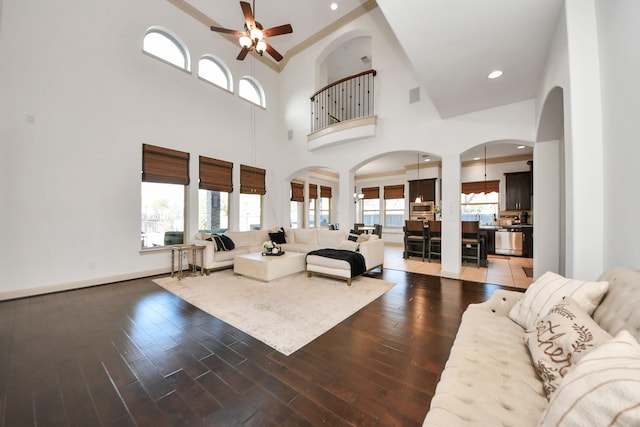 living room featuring dark hardwood / wood-style flooring, a towering ceiling, and ceiling fan