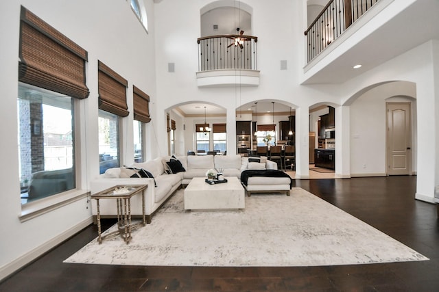 living room featuring dark wood-type flooring and ceiling fan with notable chandelier