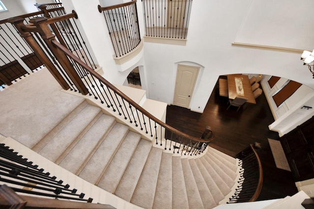 staircase with a towering ceiling and wood-type flooring