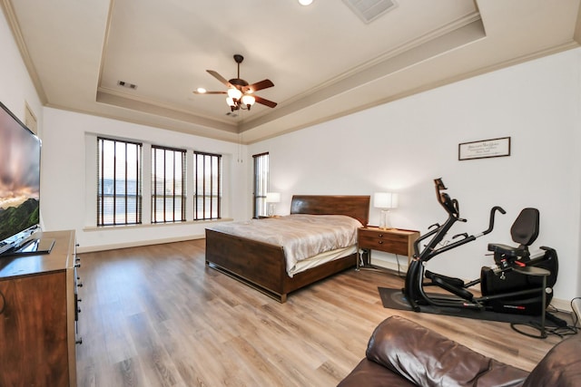 bedroom featuring ornamental molding, light hardwood / wood-style floors, and a tray ceiling