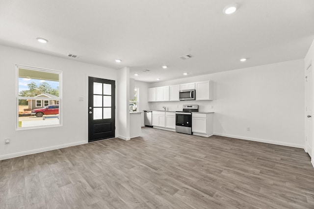 unfurnished living room featuring sink and light wood-type flooring