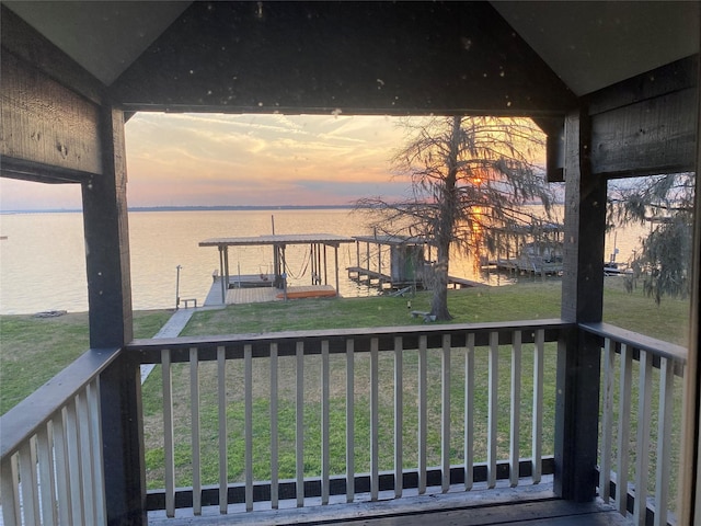 deck at dusk featuring a water view and a yard