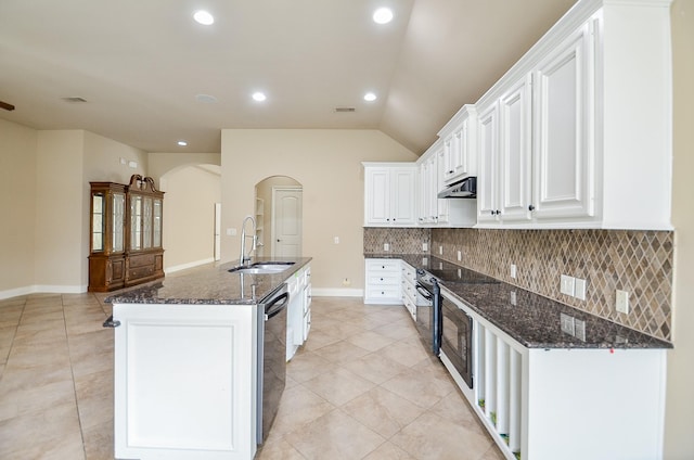 kitchen with sink, tasteful backsplash, dark stone countertops, an island with sink, and white cabinets