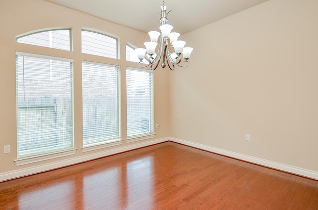 empty room featuring hardwood / wood-style floors and a chandelier