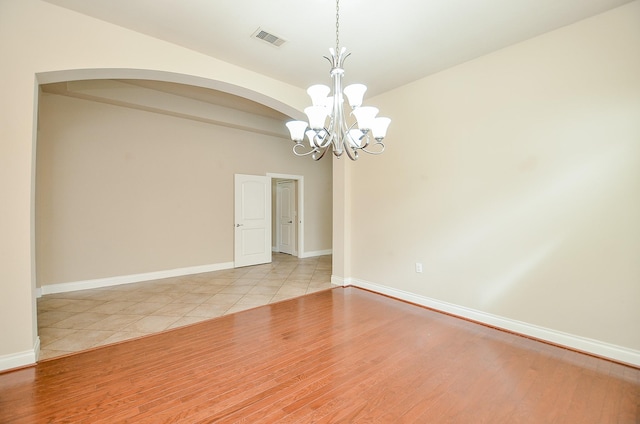 tiled spare room with a notable chandelier