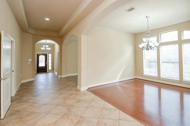 tiled entrance foyer with a notable chandelier and a tray ceiling