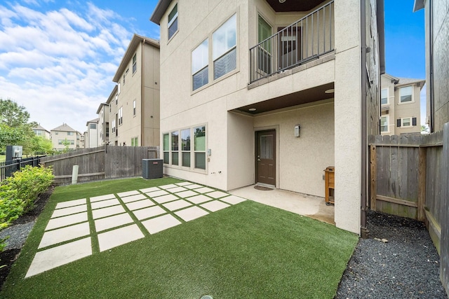 rear view of property featuring cooling unit, a yard, and a patio area