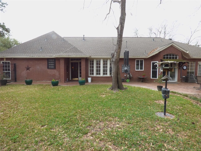 back of house featuring a patio area, a lawn, brick siding, and roof with shingles