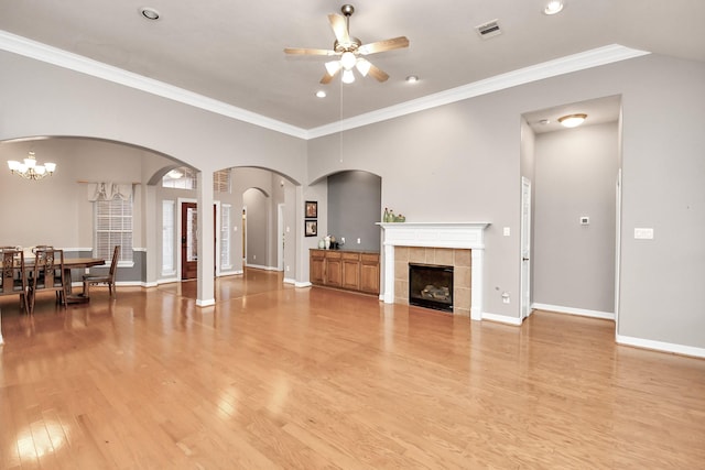 living room featuring crown molding, ceiling fan with notable chandelier, a fireplace, and light wood-type flooring